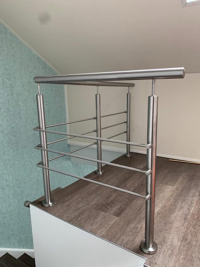 Innenliegendes Treppengeländer aus Edelstahl mit rundem Handlauf